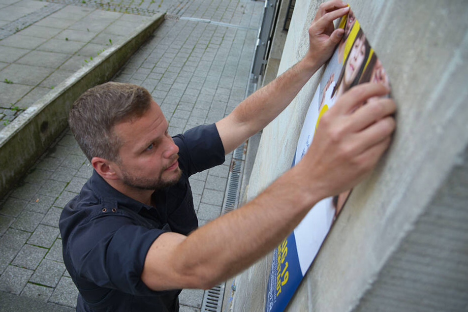 Michael Specht (34) bringt in der Stadt ein Plakat für das Chemnitzer Bürgerfest an.