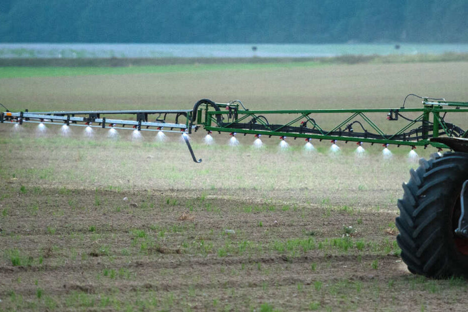 Ein Landwirt fährt mit einer Pestizid- und Düngerspritze über ein Feld.