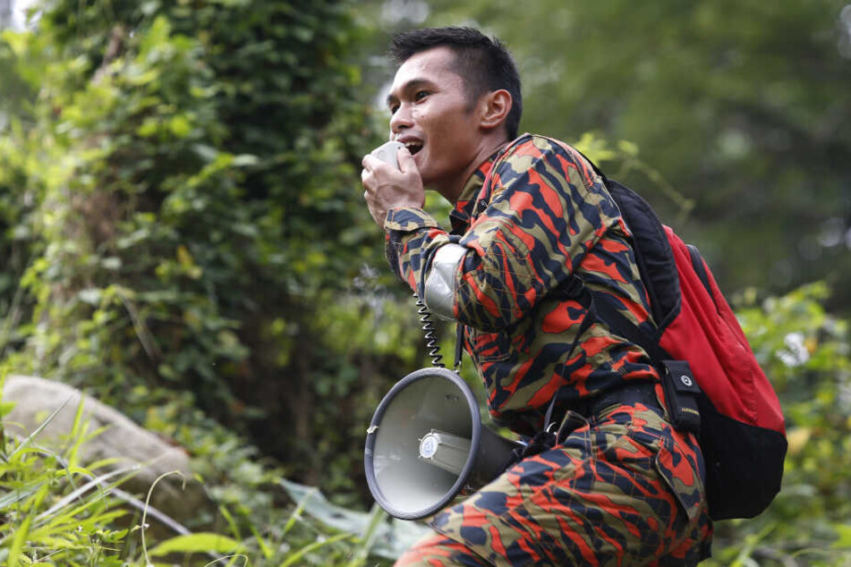 Ein Mitglied eines Rettungsteams benutzt einen Lautsprecher bei einer Such- und Rettungsaktion für ein vermisstes britisches Mädchen in einem Wald in Seremban, Negeri Sembilan.