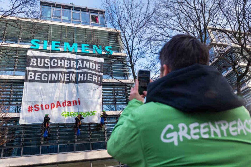 Ein Mann hält die Aktion der Aktivsten mit seinem Handy fest.