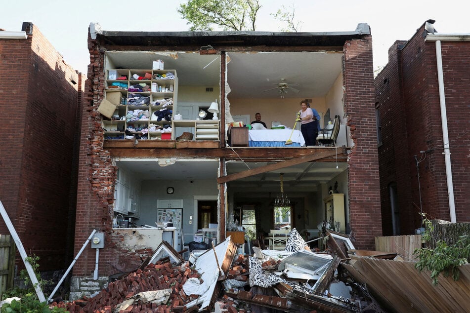 Residents inspect their home after a tornado completely tore off the back wall of a two-story house in St. Louis, Missouri, on May 16, 2025.