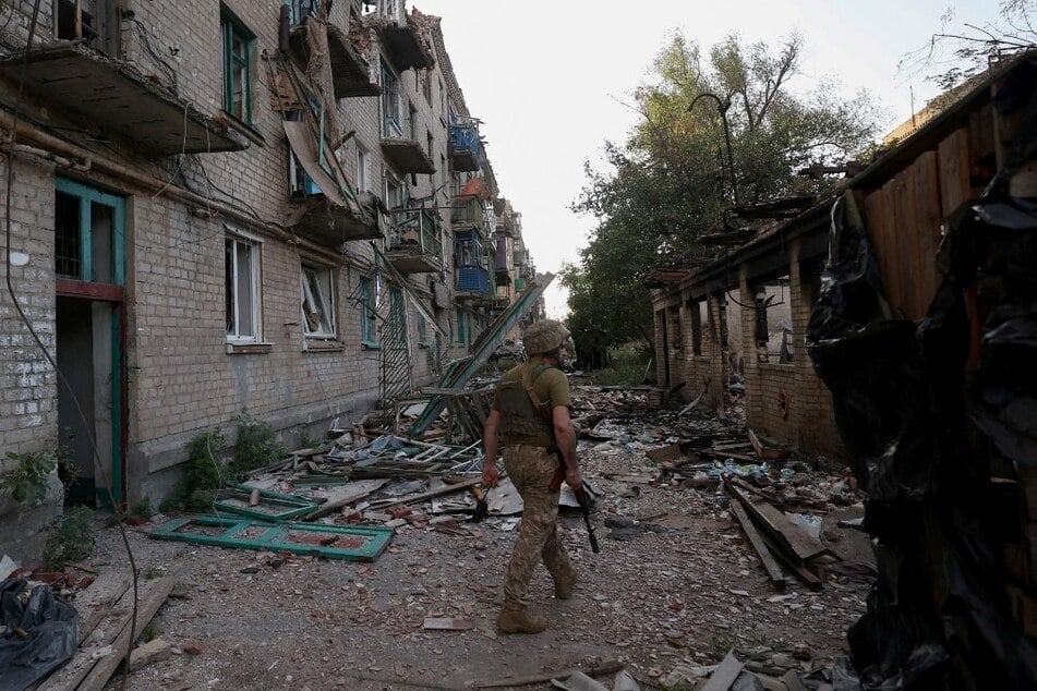 A Ukrainian serviceman of the 225th Separate Assault Battalion patrols as he walks past buildings heavily damaged by artillery fire in the town of Chasiv Yar, Donetsk region.