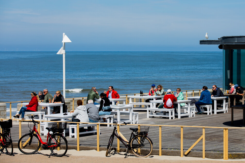 Urlauber genießen die Sonne auf der Terrasse der Milchbar auf Norderney.