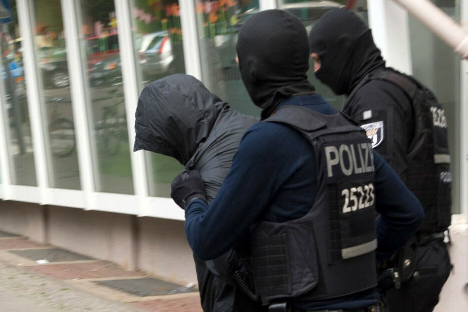 Polizisten führen einen der Verdächtigen des Gold-Münzen-Raubes ab.