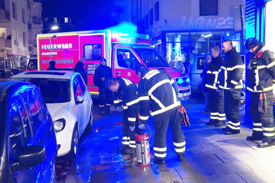 Feuerwehrleute entfernen das Blut von der Straße, während im Rettungswagen ein Verletzter versorgt wird.