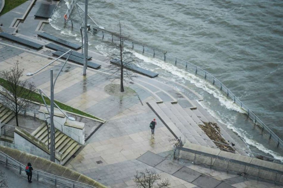 Fußgänger gehen bei Sturm und Regen durch die Hamburger Hafencity