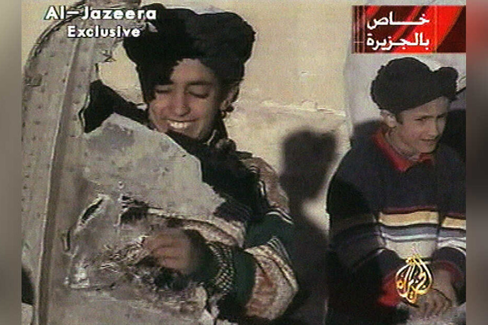 Ein Al-Jazeera-Video vom 07.11.2001 zeigt Hamsa bin Laden (l) in Ghazni (Afghanistan), der nach Angaben der Taliban Teile eines zerstörten US-Hubschraubers hält. Hamsa bin Laden war in terroristische Aktivitäten involviert.