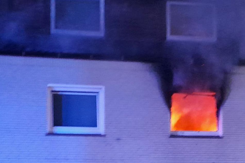 Flammen schlagen aus Fenster, als die Feuerwehr plötzlich einen Bewohner sieht