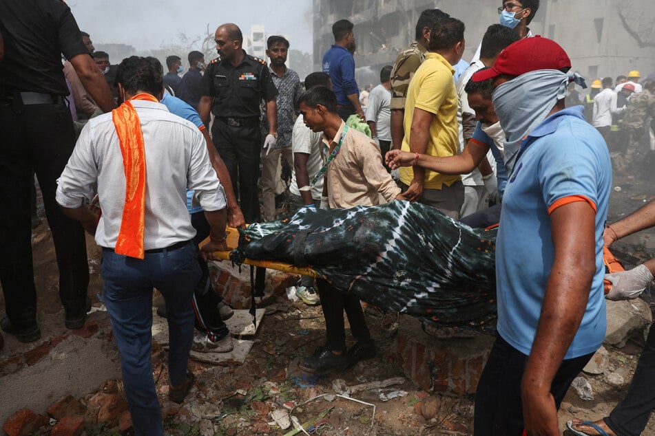 People carry the body of a victim from the crash site after an Air India Boeing 787 Dreamliner plane crashed in Ahmedabad, India.