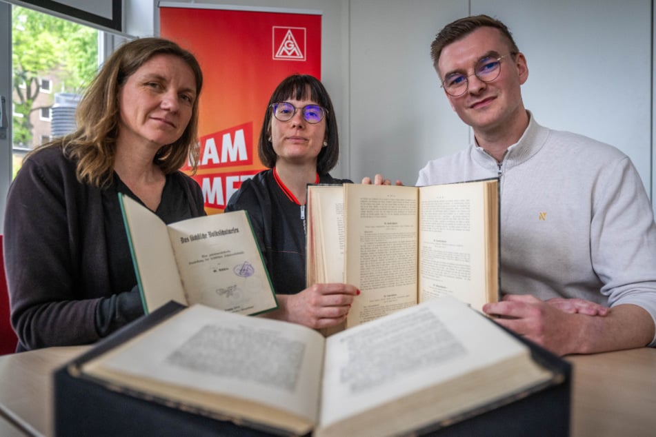 Lydia Oeser (46, v. l.), Leiterin der Stadtbibliothek Burgstädt und Elisabeth Geldmacher (35), wissenschaftliche Mitarbeiterin der SLUB Dresden überreichen Eddie Kruppa (32), Erster Bevollmächtigter der Chemnitzer IG Metall, einst von den Nazis geraubte Bücher.