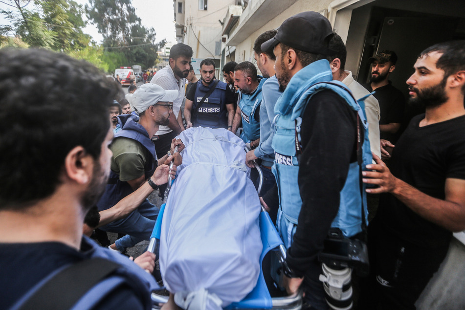 Personen tragen die Leiche eines palästinensischen Journalisten, der bei der Arbeit durch israelische Luftangriffe in Gaza getötet wurde.