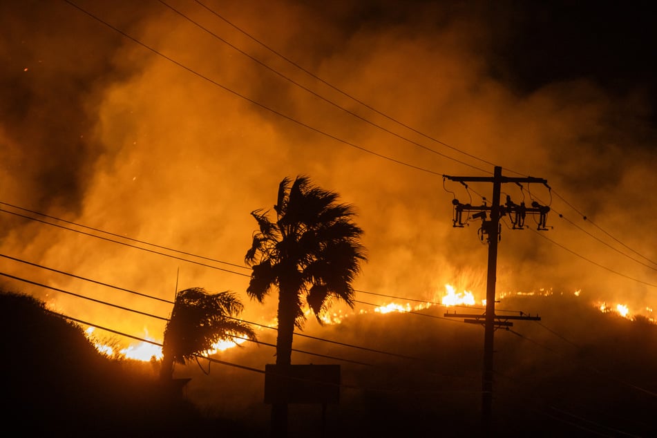 The Franklin Fire burns next to powerlines at the Pacific Coast Highway in the morning on Wednesday near Malibu, California.