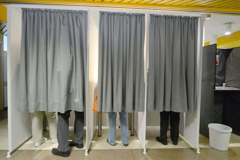 Wähler stehen in einer Wahlkabine.
