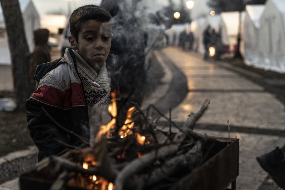 Ein Junge wärmt sich neben einem Feuer in einem Lager für Überlebende des Erdbebens in Gaziantep.