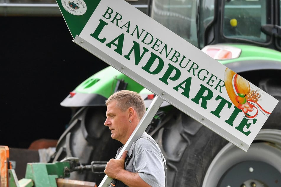 Trecker-Fan Ralf Wittke trägt im Juni 2018 ein Schild mit der Aufschrift "Brandenburger Landpartie", über seinen Hof. (Archivbild)