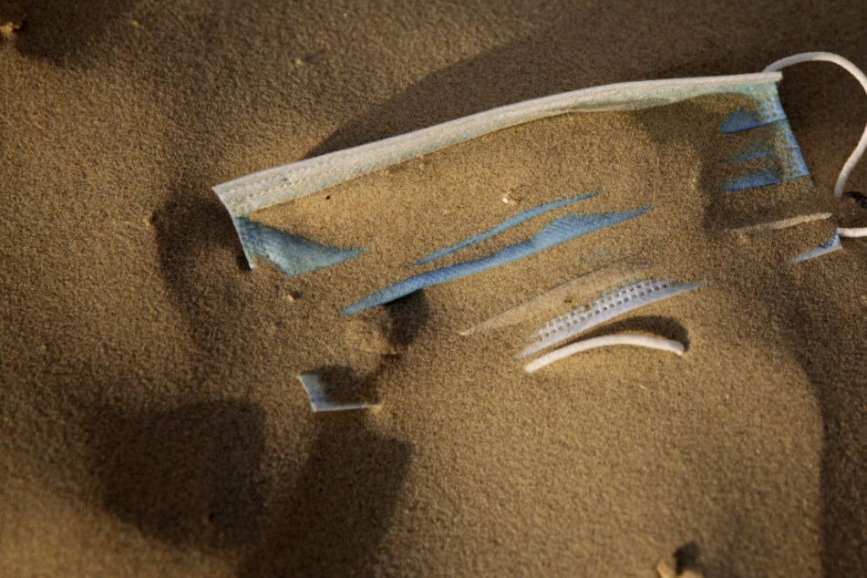 Eine Atemschutzmaske liegt im Sand. (Archivbild)