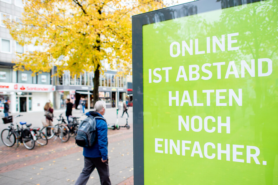 Ein Mann geht in der Innenstadt Hannovers an einer Werbetafel mit der Aufschrift "Online ist Abstand halten noch einfacher" vorbei.