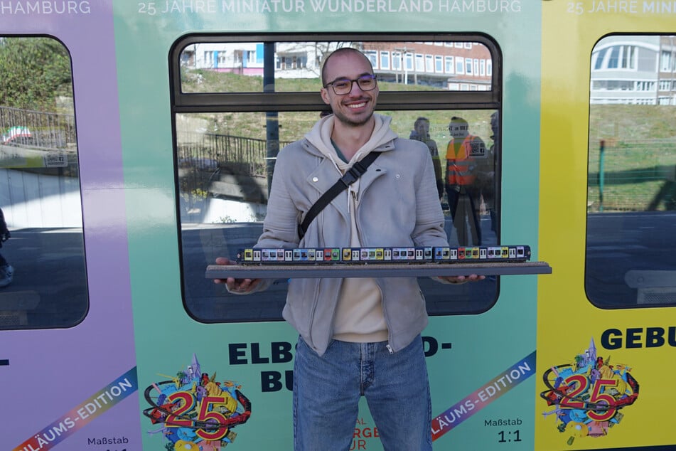 Wunderland-Mitarbeiter Fabian Althaus präsentiert stolz "sein" Modell der Wunderland-S-Bahn vor dem Originalzug.