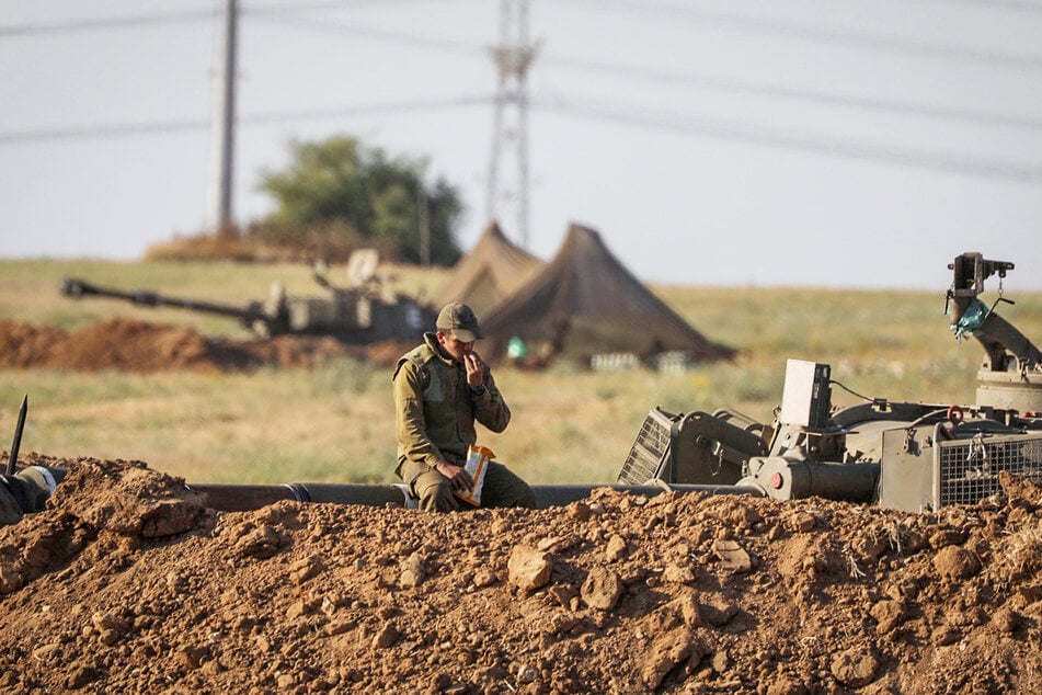 Ein Soldat der Israelischen Verteidigungsstreitkräfte (IDF) ruht sich auf einem Rohr einer Artilleriebatterie aus.