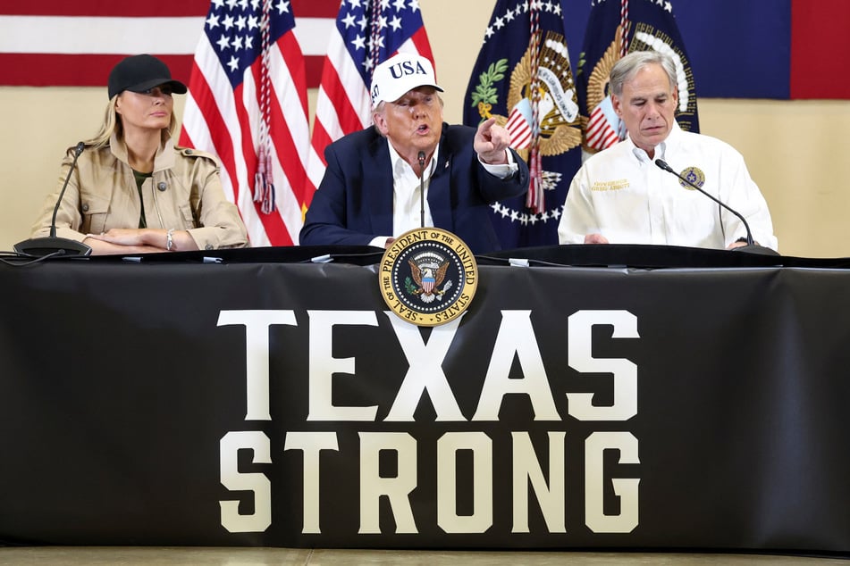 President Trump (c.) has brushed off questions about the impact of his cuts to federal agencies on the response to the flood, which he described as a "100-year catastrophe" that "nobody expected."