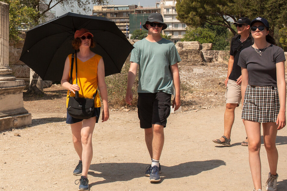 Weil in Griechenland Temperaturwerte von mehr als 40 Grad erreicht werden, schützen sich manche Touristen schon mit Sonnenschirmen.