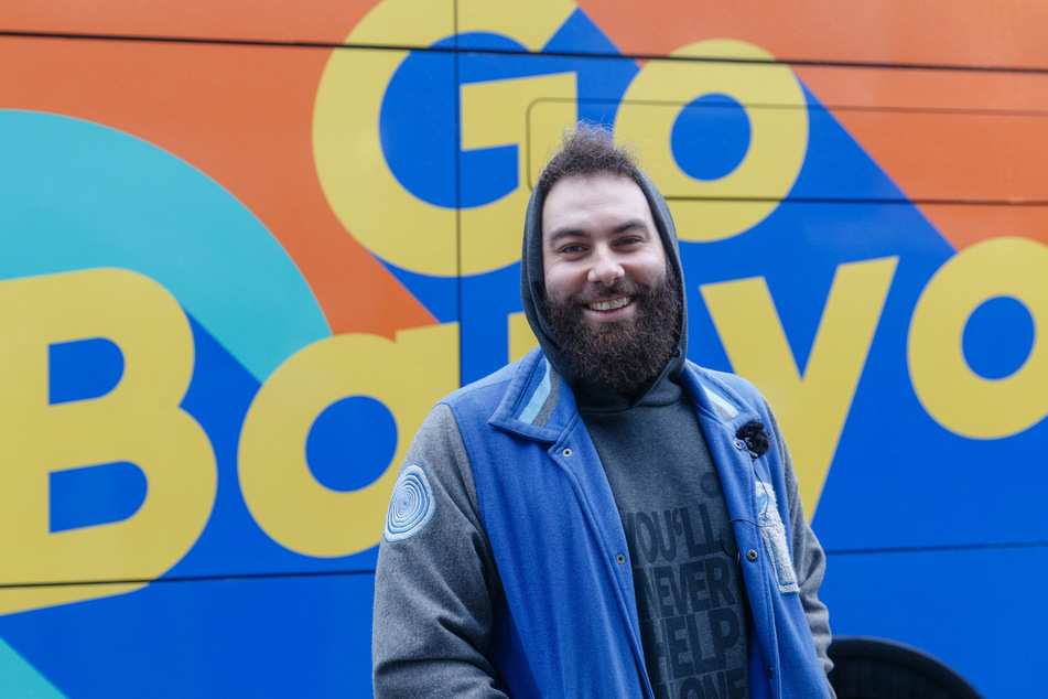 Dominik Bloh (34) steht vor dem Logo "GoBanyo" des Duschbusses.
