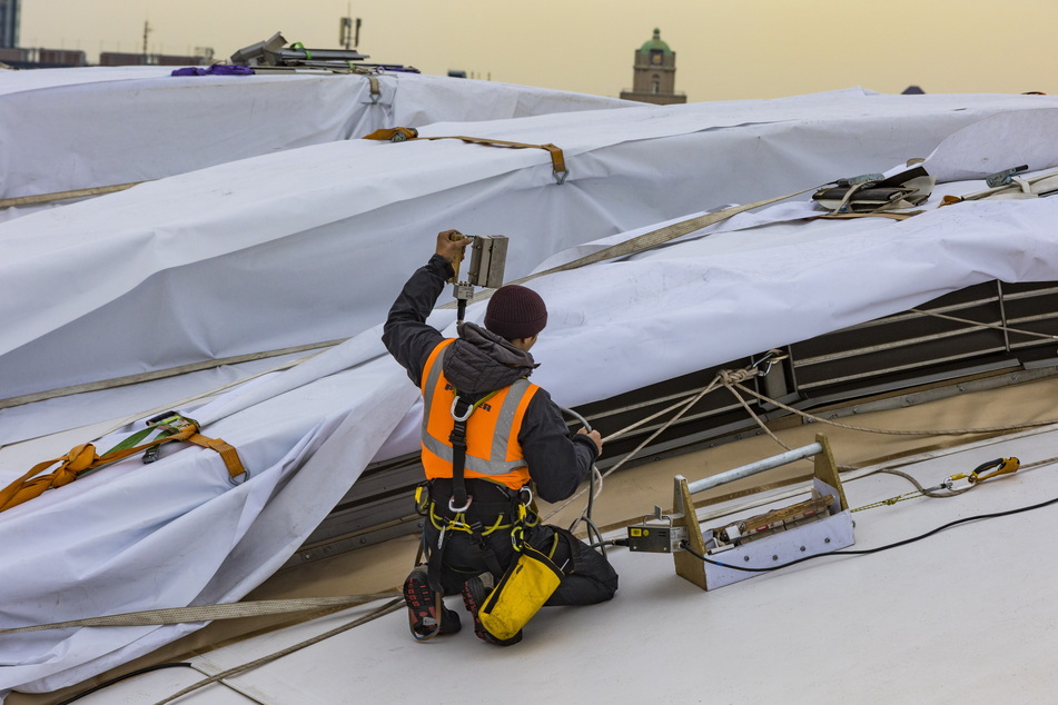 Ein Arbeiter erledigt Restarbeiten auf dem Dach.