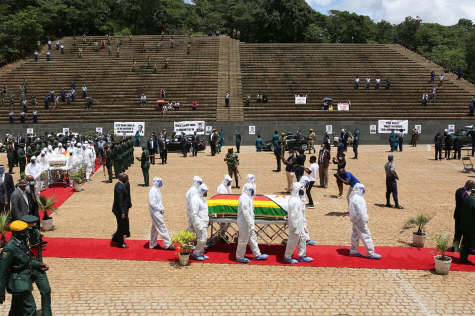Simbabwe, Harare: Menschen in Schutzkleidung tragen den Sarg der an Corona verstorbenen Ministerin Dr. Ellen Gwaradzimba über die Grabstätte "Heroes Acre".