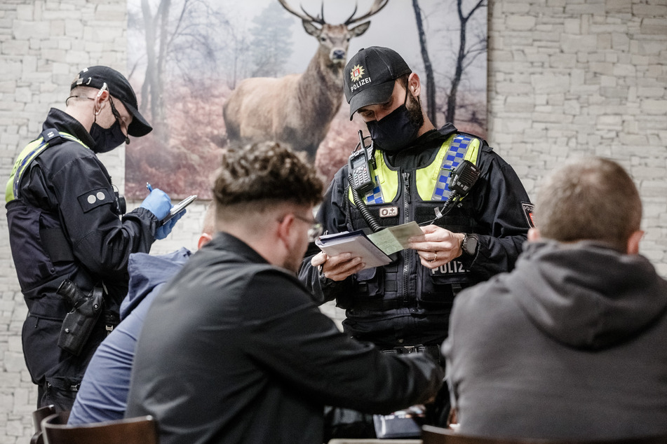 Polizisten kontrollieren in einer Bar die Einhaltung der Corona-Vorgaben.
