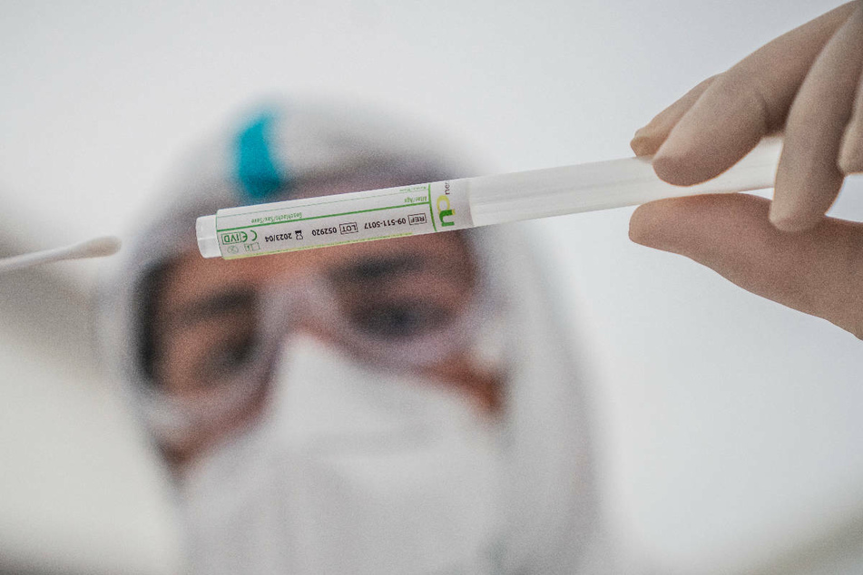Ein Mitglied des medizinischen Personals in einem Corona-Testzentrum steckt ein Wattestäbchen nach einem PCR-Abstrich zum Test auf Covid-19 in ein Röhrchen. In Berlin gibt es in der Pandemie wieder mehr Labortests auf das Sars-CoV-2-Virus.