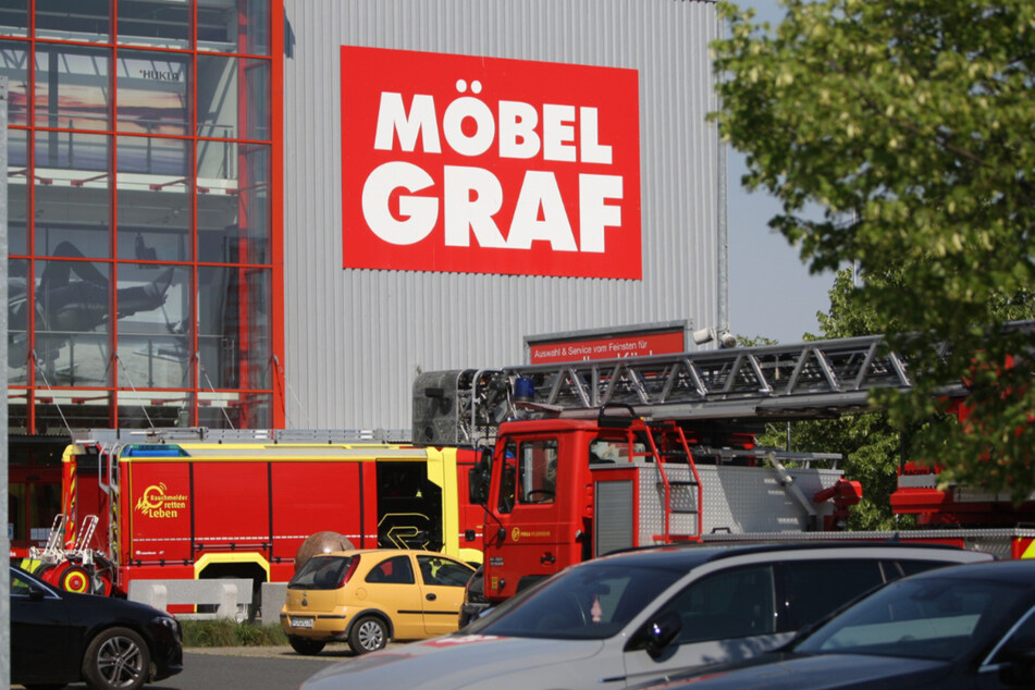 Fahrzeuge der Feuerwehr stehen vor dem Möbelhaus.