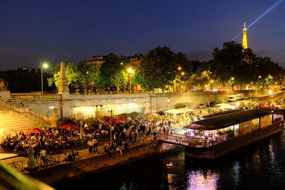 Besucher sitzen am Ufer der Seine und essen und trinken. In Frankreich dürfen Bars und Restaurants ihre Terrassen unter der Einhaltung von Sicherheitsmaßnahmen wieder öffnen.