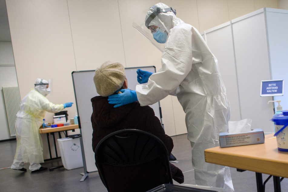Mitarbeiter des Universitätsklinikums Magdeburg führen bei einer Frau einen Antigentest auf das Coronavirus durch.