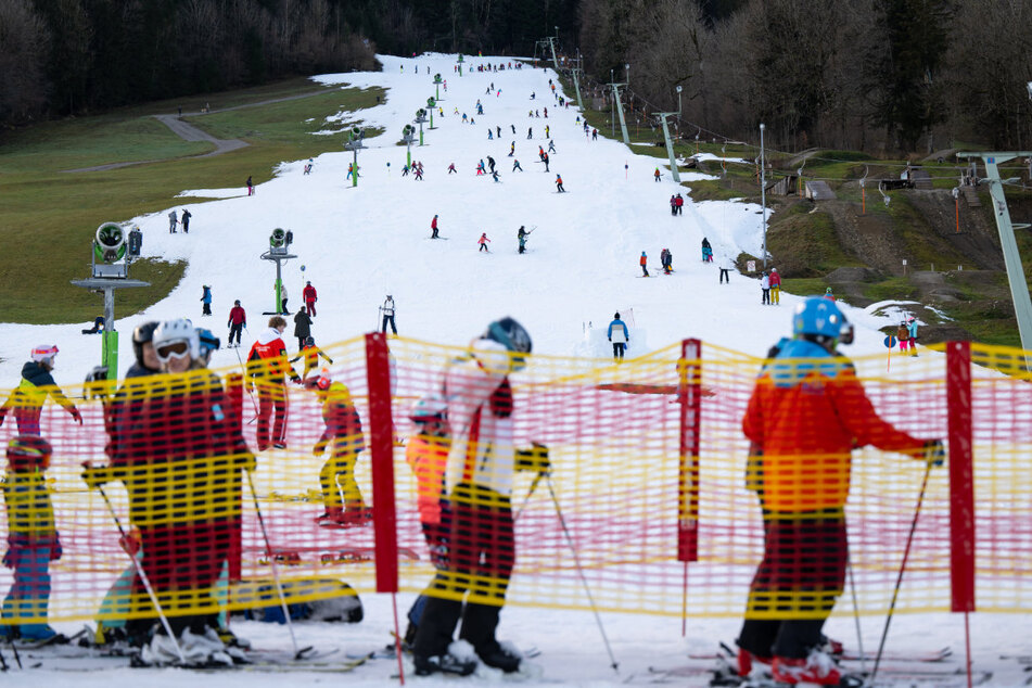Wintersportler stehen im bayerischen Skigebiet Brauneck an einem Lift an, um die kleine Schneefläche nutzen zu können.