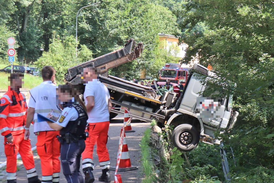 Polizisten und Rettungskräfte inspizieren den Unfallort, an dem der Lkw in die Böschung fiel.