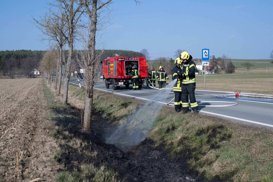 Die Feuerwehr löscht einen in Brand geratenen Straßengraben.