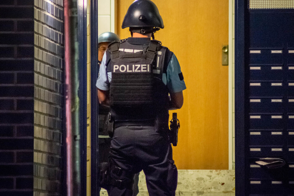 Polizisten stehen im Eingang des Mehrfamilienhauses.