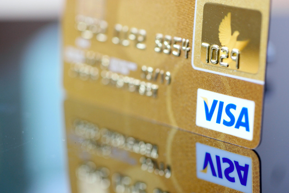 Eine Visa-Kreditkarte spiegelt sich in der Oberfläche eines Tisches.