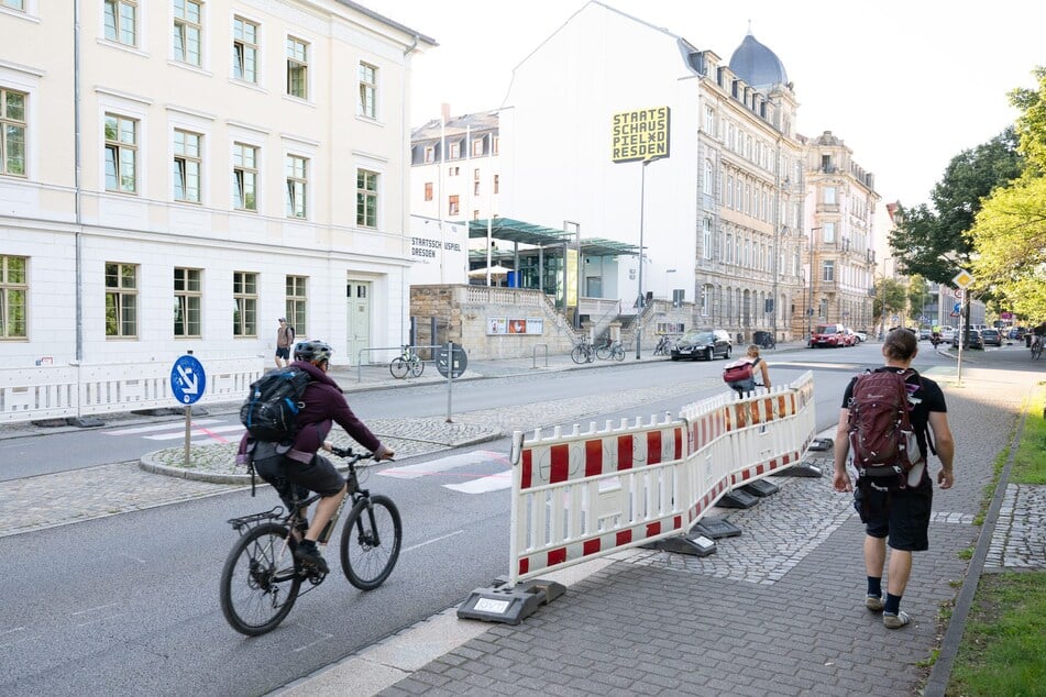 Passanten und Radfahrer fahren bzw. gehen an einem aufgemalten Zebrastreifen auf der Glacisstraße vorbei.