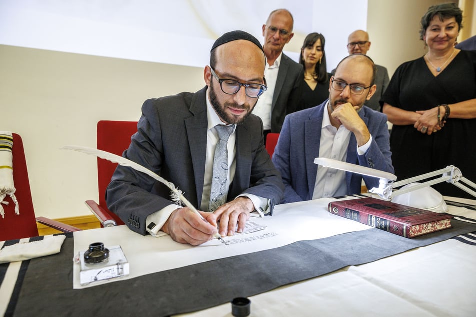 Rabbi Akiva Weingarten (40) schreibt im Rathaus mit Ehrengästen die ersten Buchstaben.