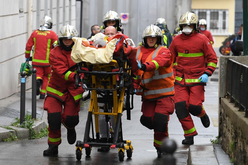 Einsatzkräfte der Feuerwehr schieben eine Trage mit einem Verletzten.