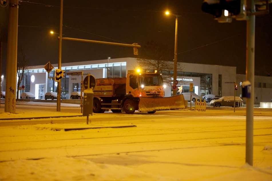 Ein Fahrzeug des Winterdienstes auf dem Weg durch die frisch beschneiten Straßen.