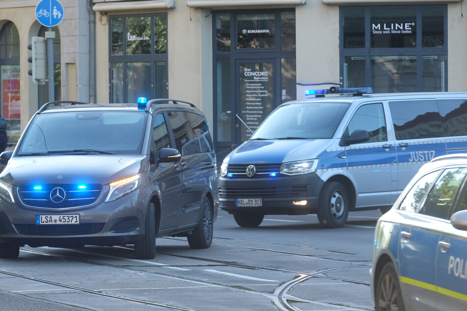 Eine Kolonne mit Fahrzeugen von Polizei und Justiz fährt mit Blaulicht und Sirene zum Landgericht Magdeburg.