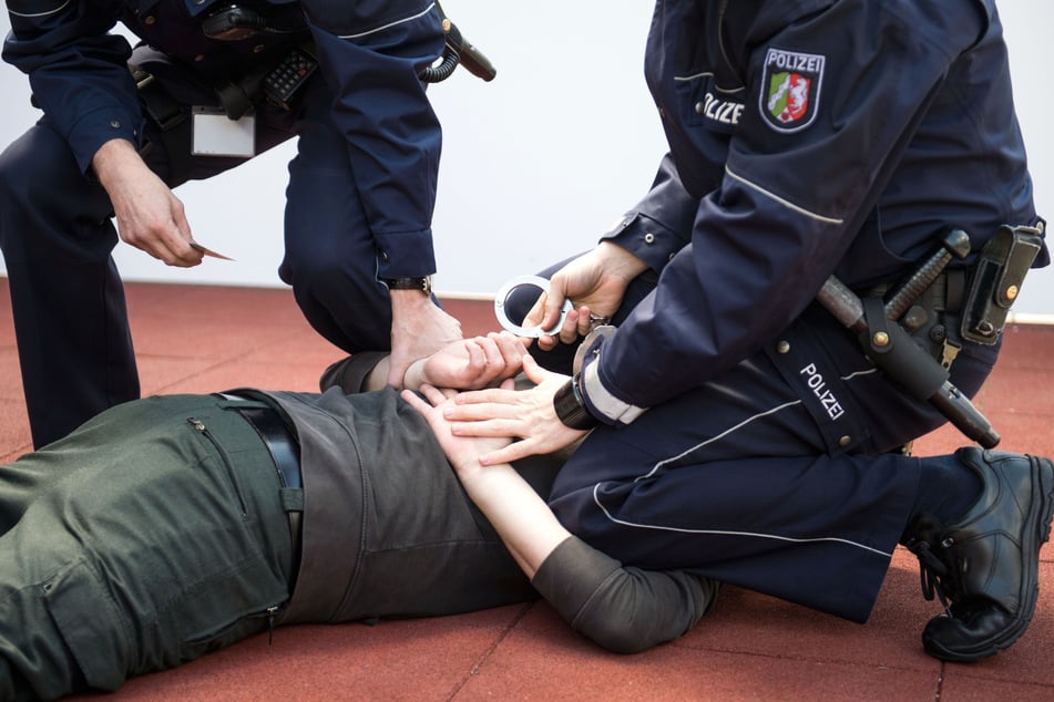 Polizisten legen einem am Boden liegenden Mann Handschellen an. (Symbolfoto)