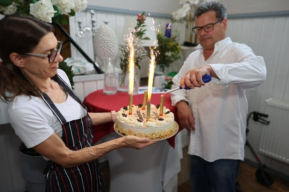 "SchnitzelLiebe"-Wirt Peter Kögler zündet die Torte an. "Ich bin stolz, dass wir eine so tolle Frau als Gast begrüßen dürfen", sagt er.