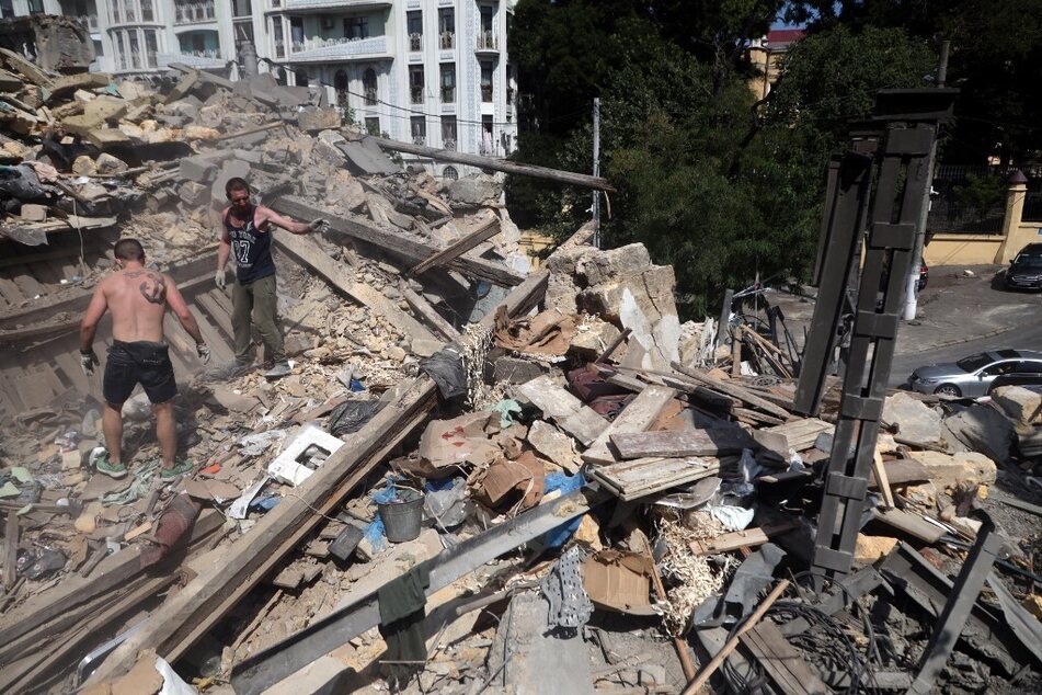 Workers clear the rubble in the center of Odessa, Ukraine, after a Russian military strike.