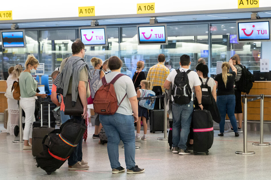 Fluggäste mit Reiseziel Mallorca stehen zur Kofferabgabe an Tui-Abfertigungsschaltern am Flughafen.