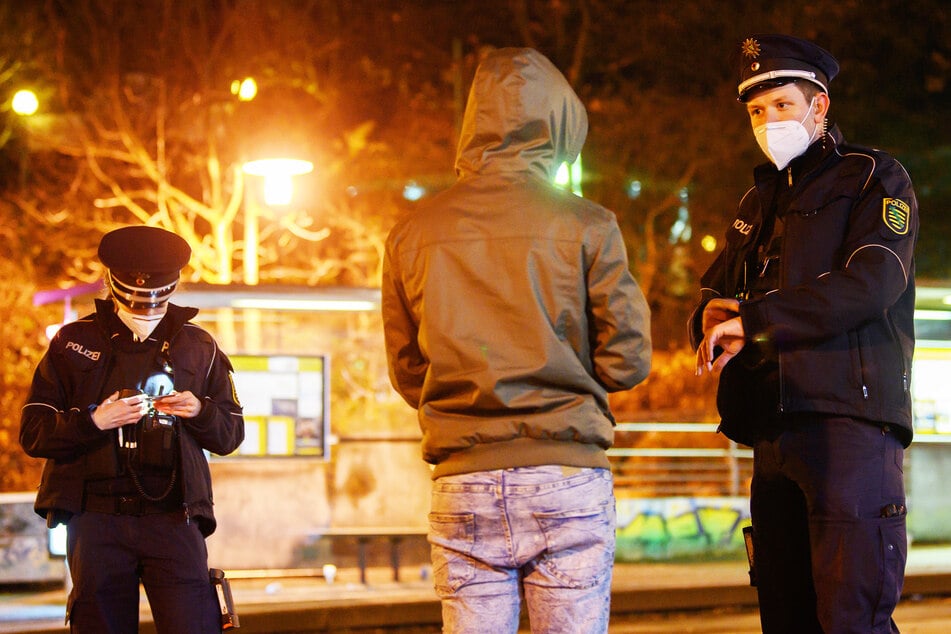 Polizisten überprüfen in der Nacht im Rahmen einer Kontrolle der Ausgangssperre einen Mann. Dies könnte ab sofort wieder häufiger passieren.