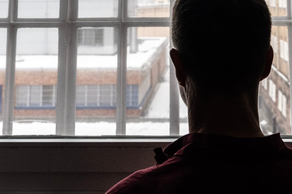 Ein 57-jähriger Häftling steht vor einem vergitterten Fenster in der JVA Butzbach und blickt auf den Innenhof. Vor mehr als elf Jahren hatte er die Mutter seiner vier Kinder getötet.