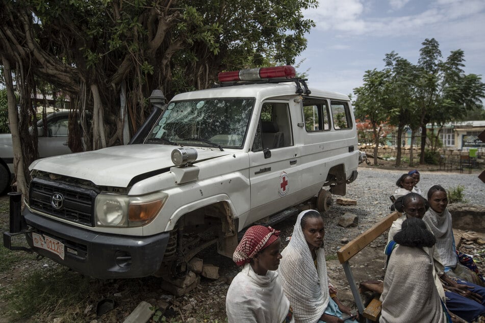 Ein Krankenwagen, der nach Angaben von Anwohnern von eritreischen Soldaten beschädigt wurde, steht neben Menschen, die im Mai 2021 vor einer Klinik in der Region Tigray auf einen Termin warten.